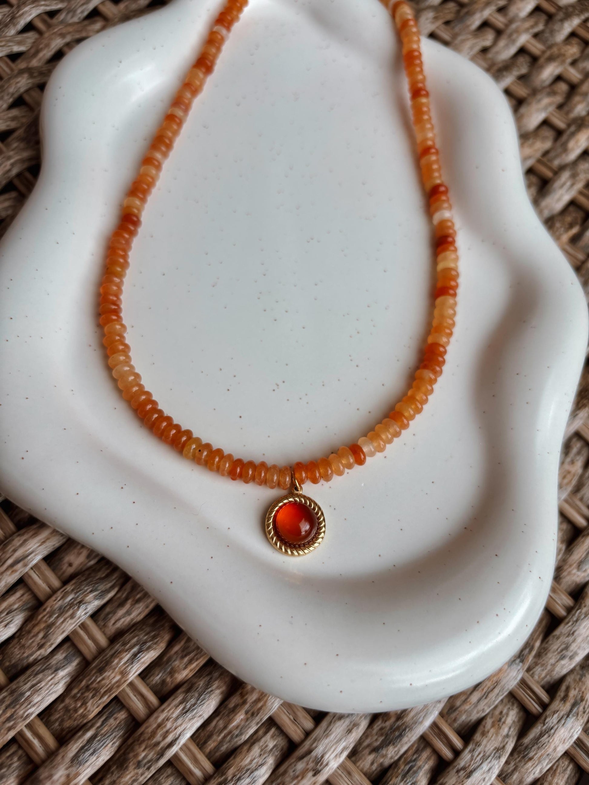 Handgemachte rote Karneol Perlen Kette mit rundem Karneol Stein Anhänger in Gold,  liegend auf Tablett