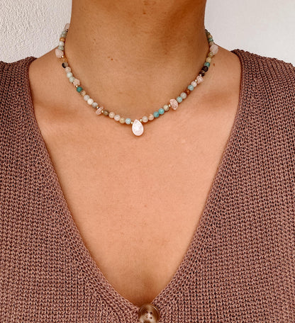 Blaue Amazonit-Perlenkette mit einem weißen facettierten Mondstein Anhänger am Dekollete eines Modells mit Häkeltop