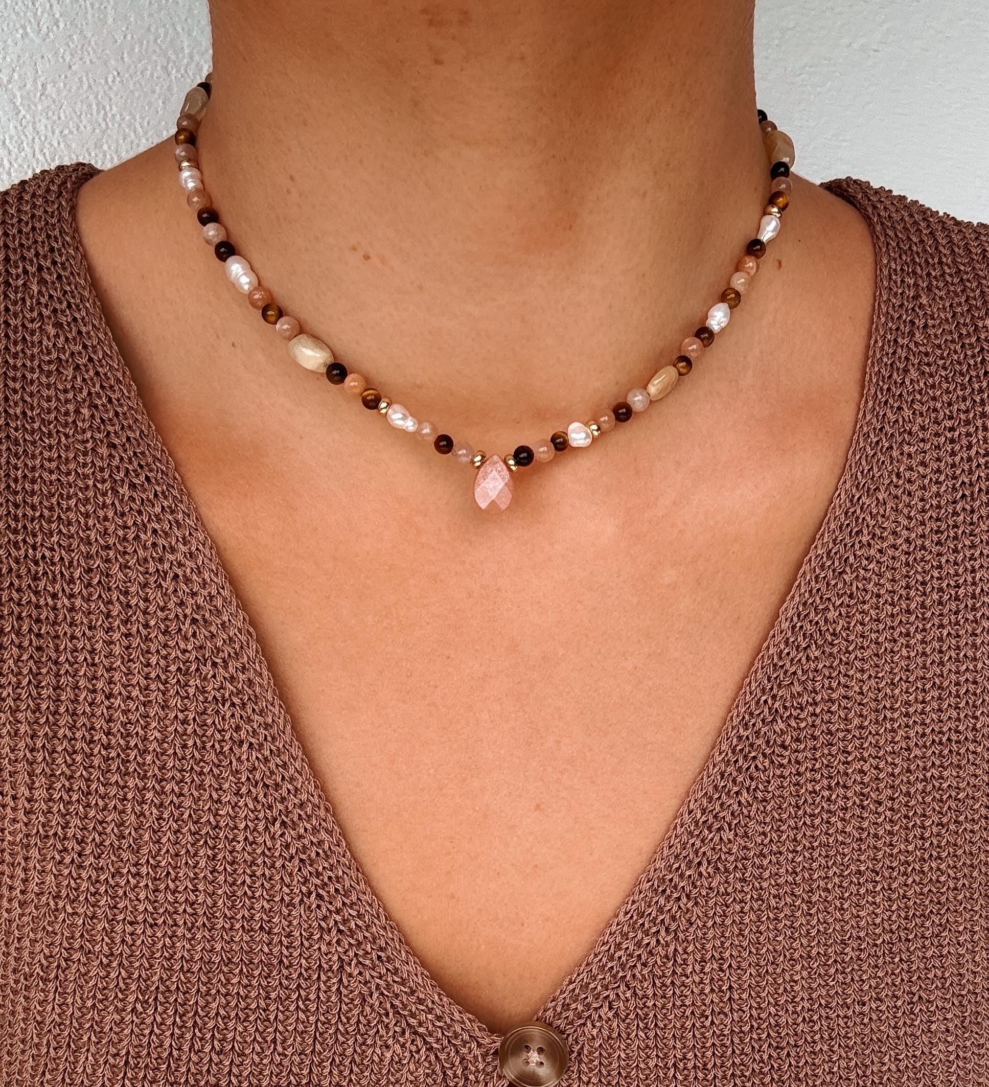 Braune Perlenkette mit Tigerauge und Sonnenstein Tropfen am Hals eines Modells