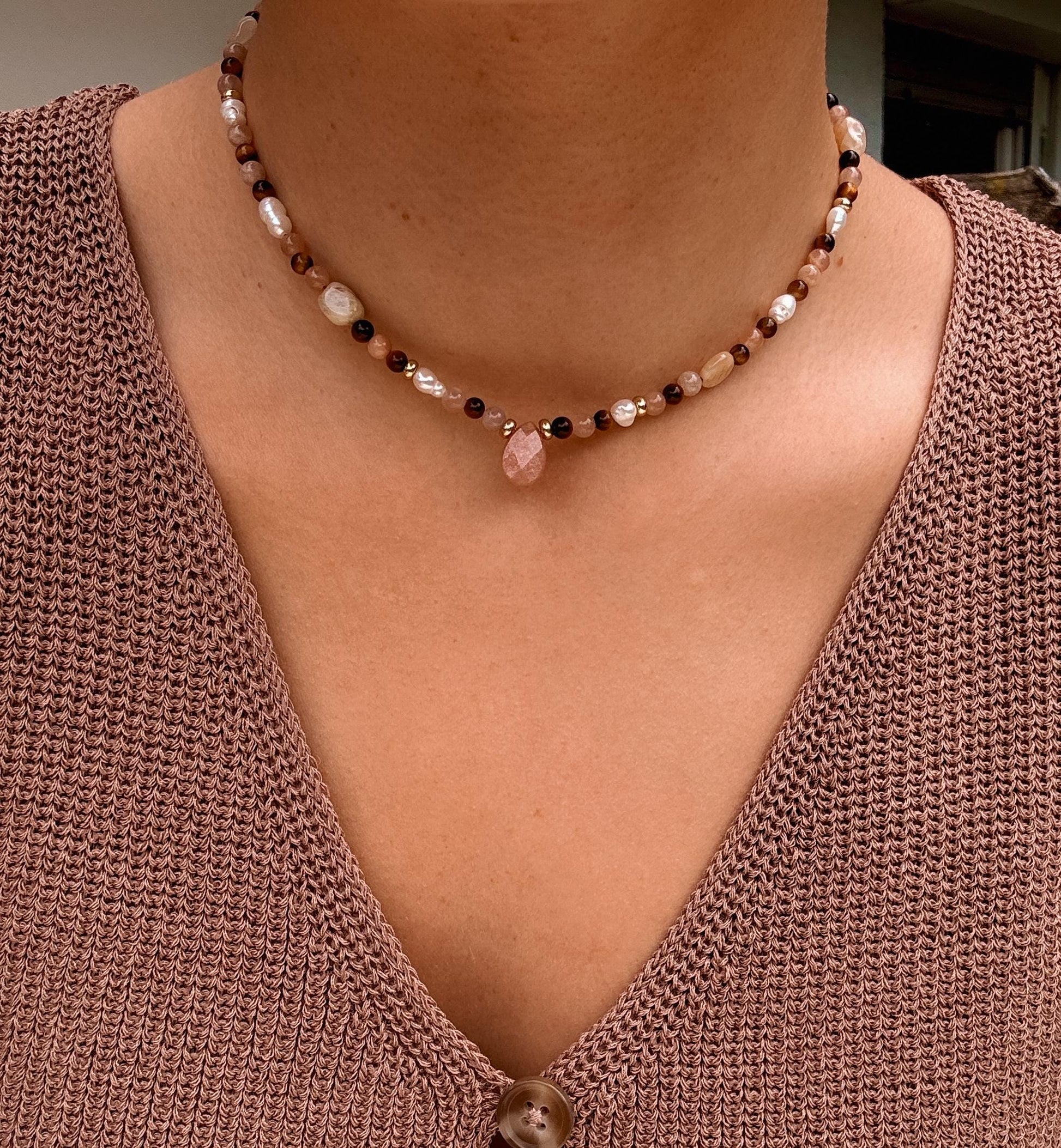 Braune Edelstein-Perlenkette mit Tigerauge und Sonnenstein Tropfen am Dekollete eines Modells