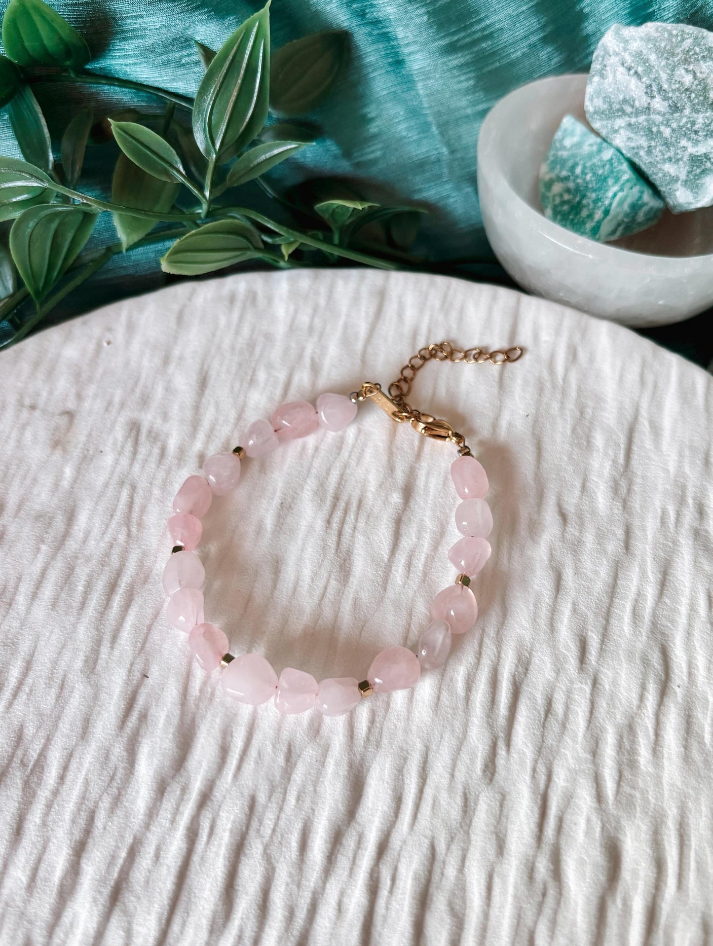 Goldenes Rosenquarz Perlenarmband mit rosa Natursteinen liegend auf weißem Tablett, Ansicht von oben