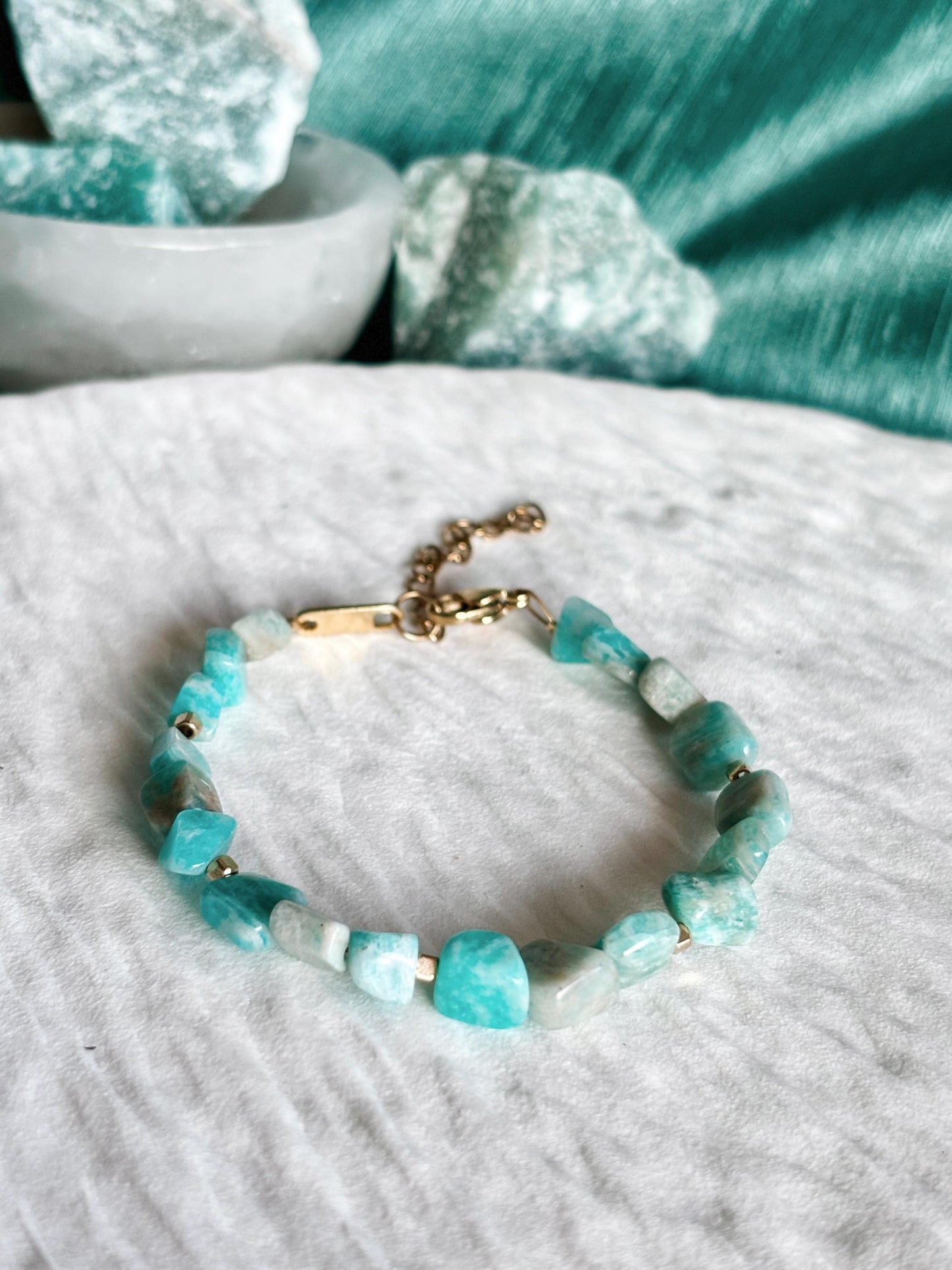 Goldenes Amazonit Perlenarmband mit blauen Natursteinen liegend auf weißem Tablett, Detailaufnahme