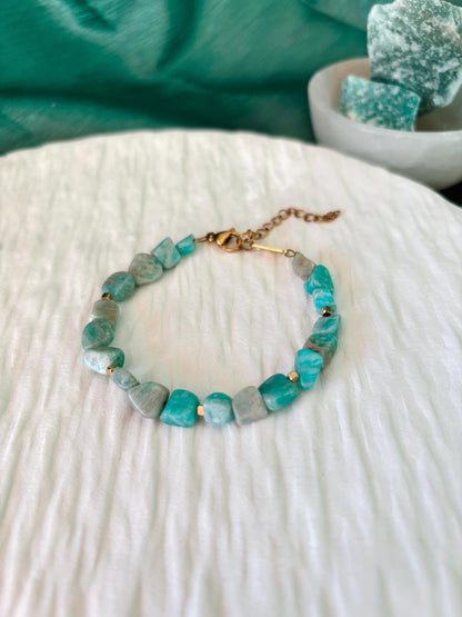 Goldenes Amazonit Perlenarmband mit türkisen Natursteinen liegend auf weißem Tablett