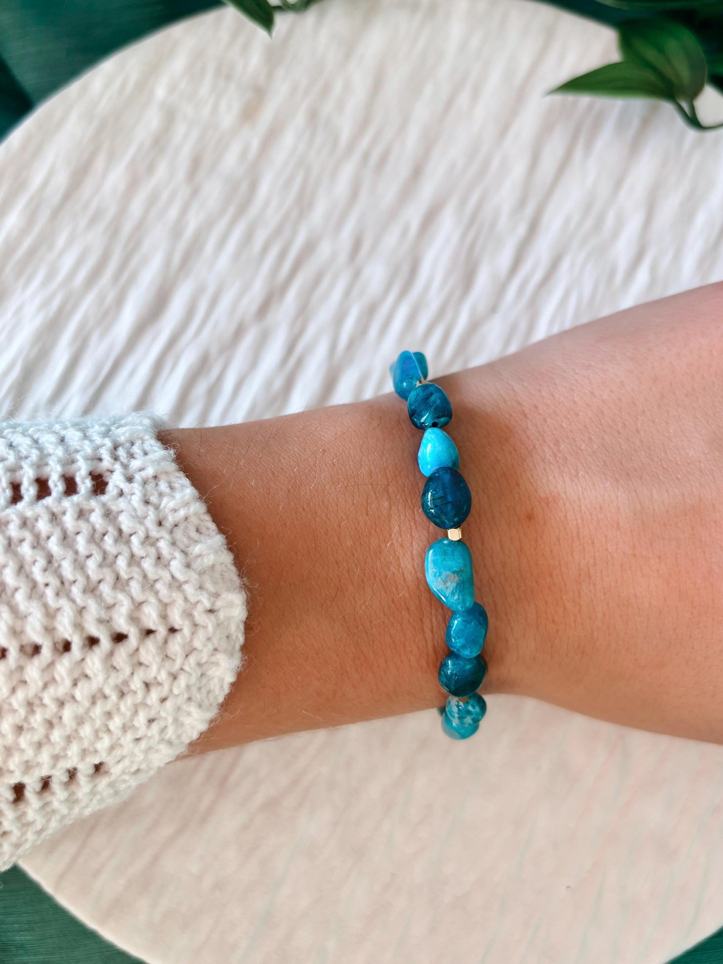 Goldenes Apatit Perlenarmband mit blauen Natursteinen am Handgelenk