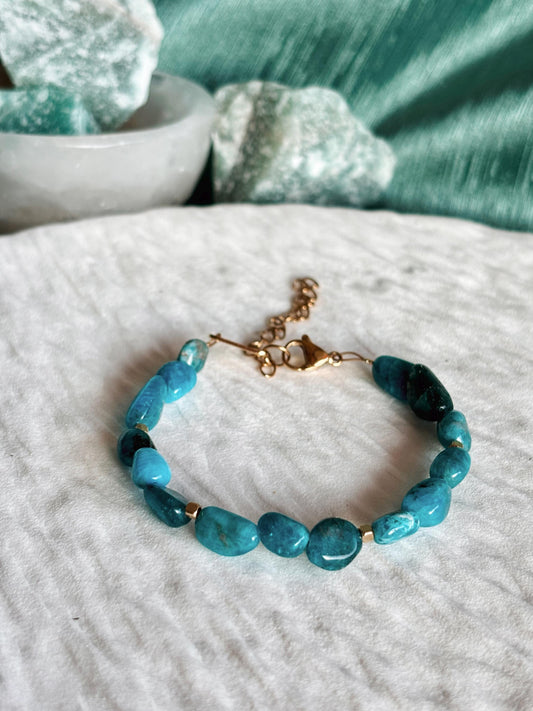 Goldenes Apatit Perlenarmband mit blauen Natursteinen liegend auf weißem Tablett, Detailaufnahme