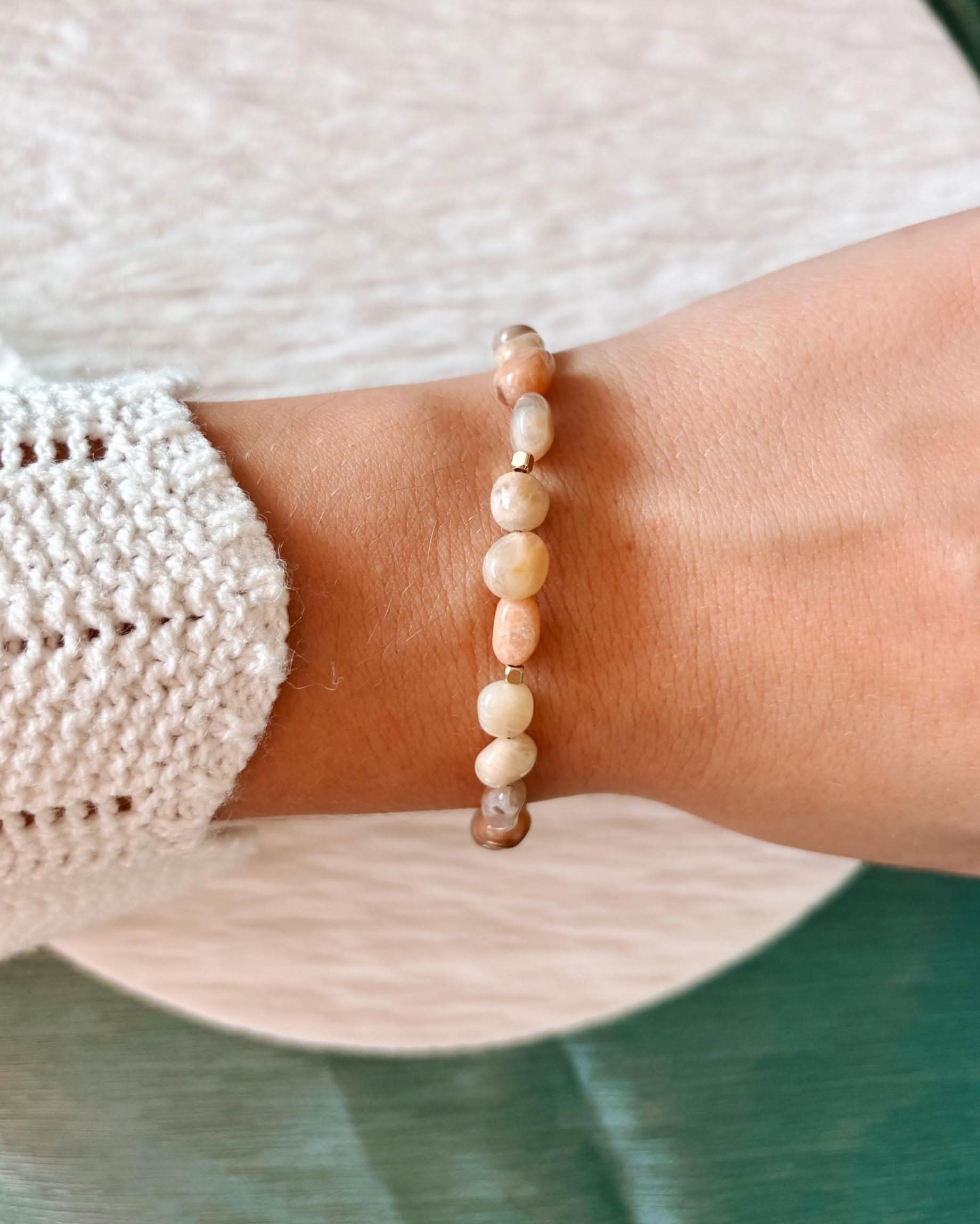 Sonnenstein-Armband Pearl an einem Handgelenk mit gestricktem Ärmel im Hintergrund.