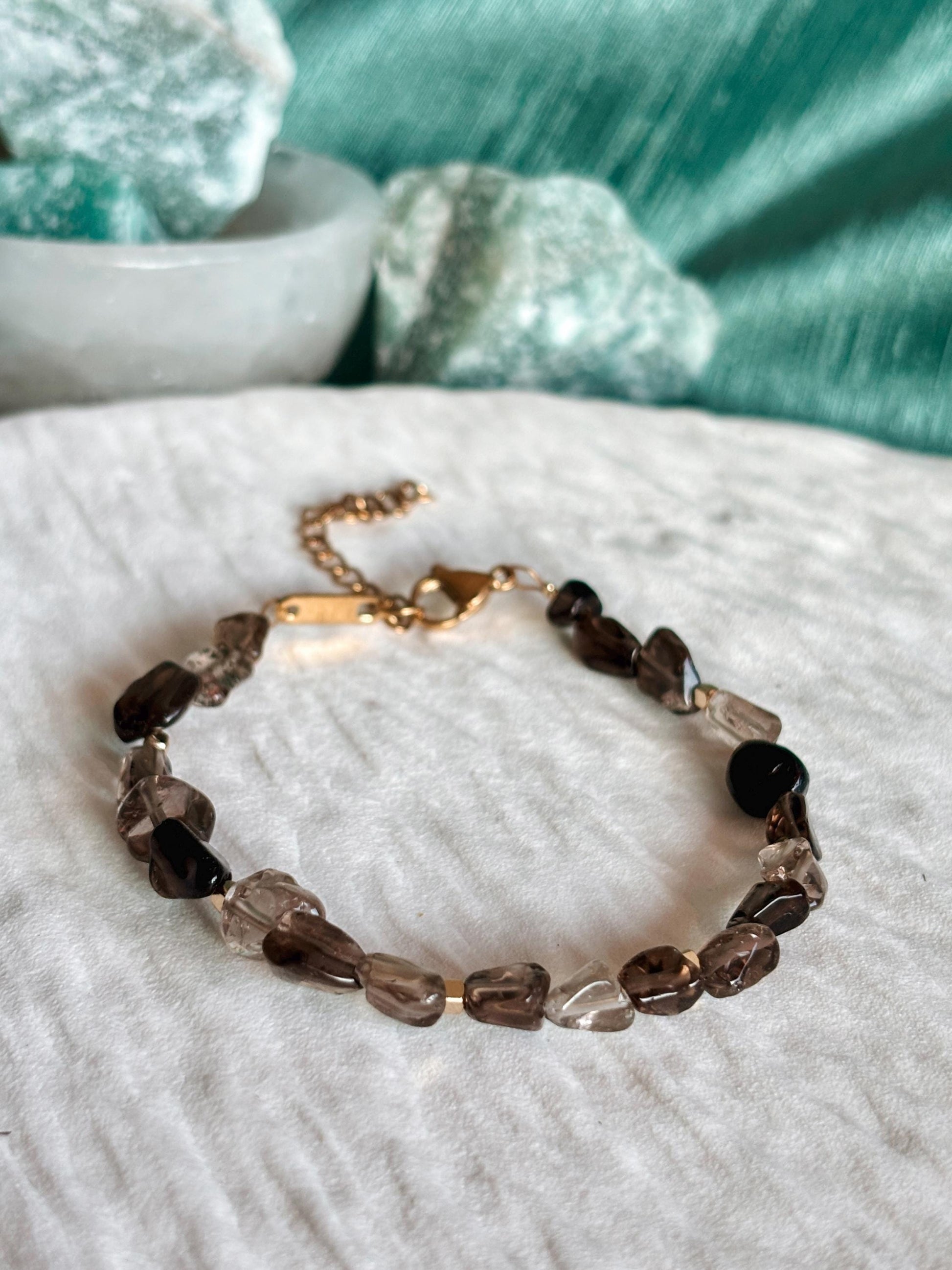 Goldenes Rauchquarz Perlenarmband mit braunen Natursteinen liegend auf weißem Tablett, Detailaufnahme