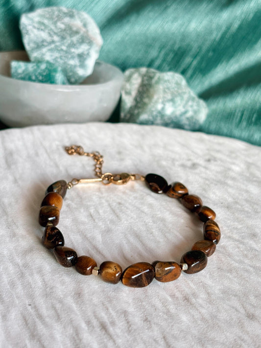 Goldenes Tigerauge Perlenarmband mit braunen Natursteinen liegend auf weißem Tablett, Detailaufnahme