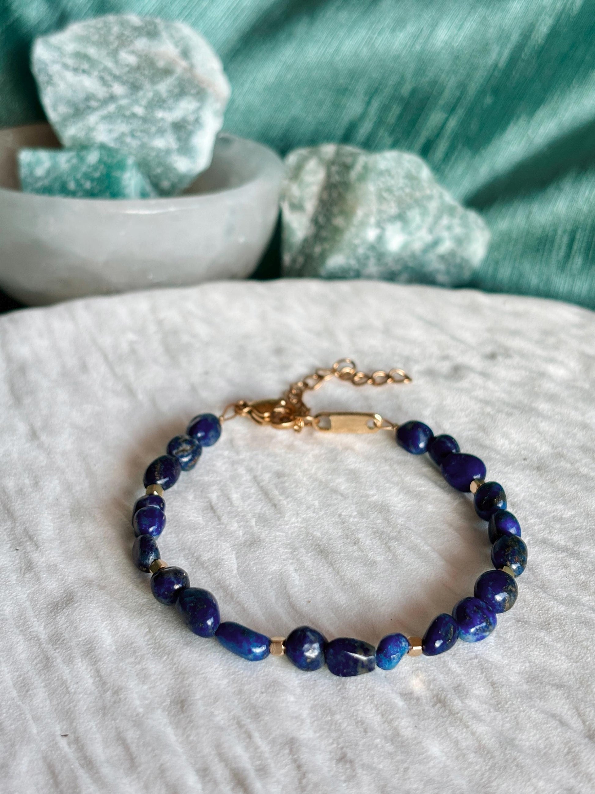 Goldenes Lapislazuli Perlenarmband mit blauen Natursteinen liegend auf weißem Tablett, Detailaufnahme