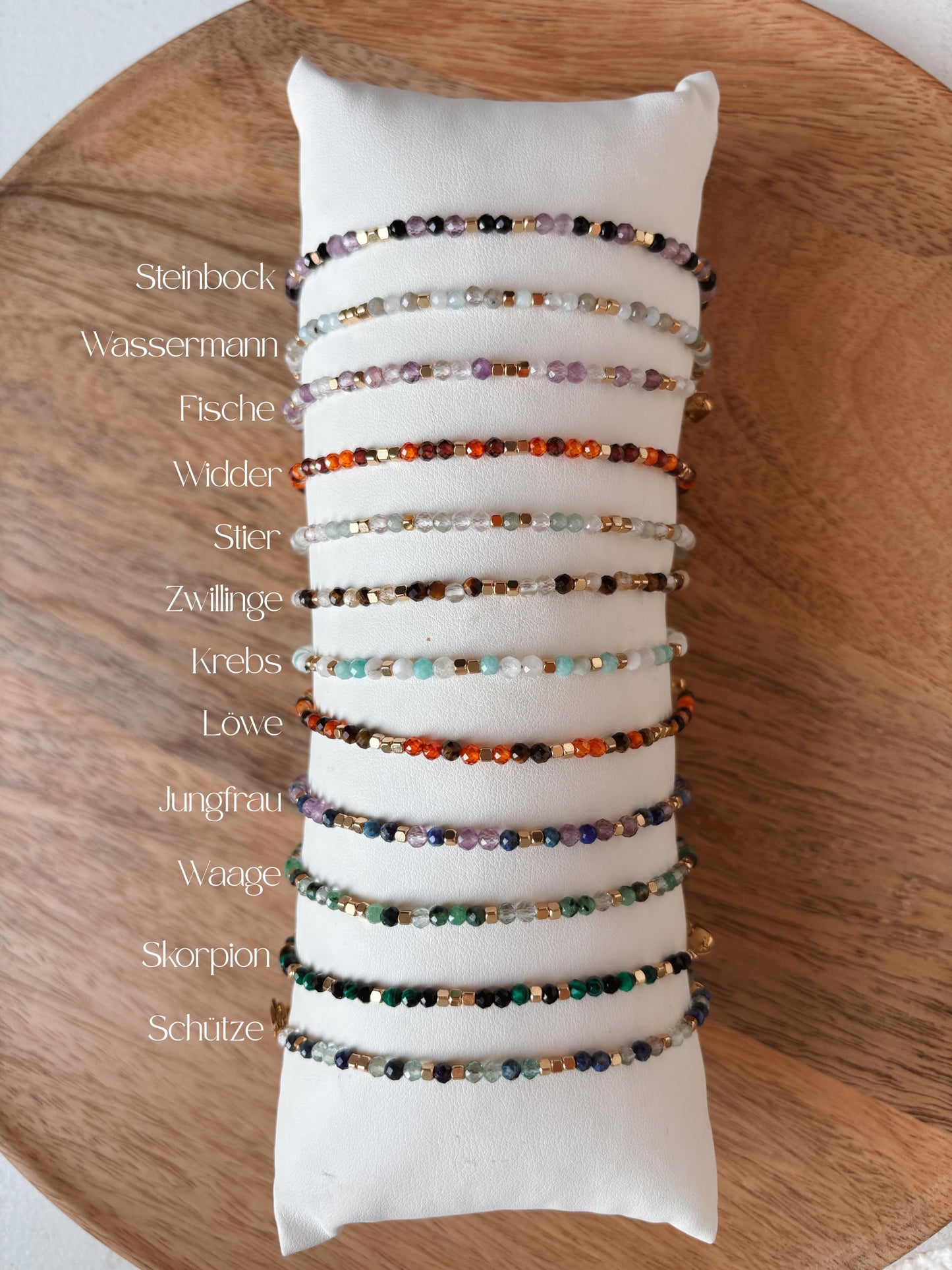 Sternzeichen Armbänder mit bunten Edelstein Perlen aufgereiht auf Schmuckkissen