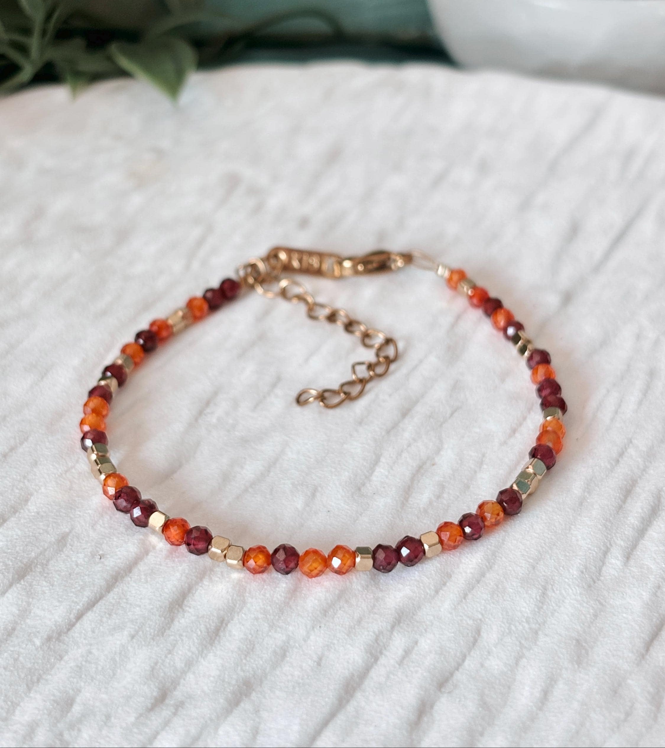 Goldenes Edelstein Armband mit Granat und Karneol Perlen liegend auf weißem Tablett, Detailansicht