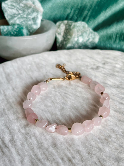 Goldenes Rosenquarz Perlenarmband mit rosa Natursteinen liegend auf weißem Tablett, Detailaufnahme