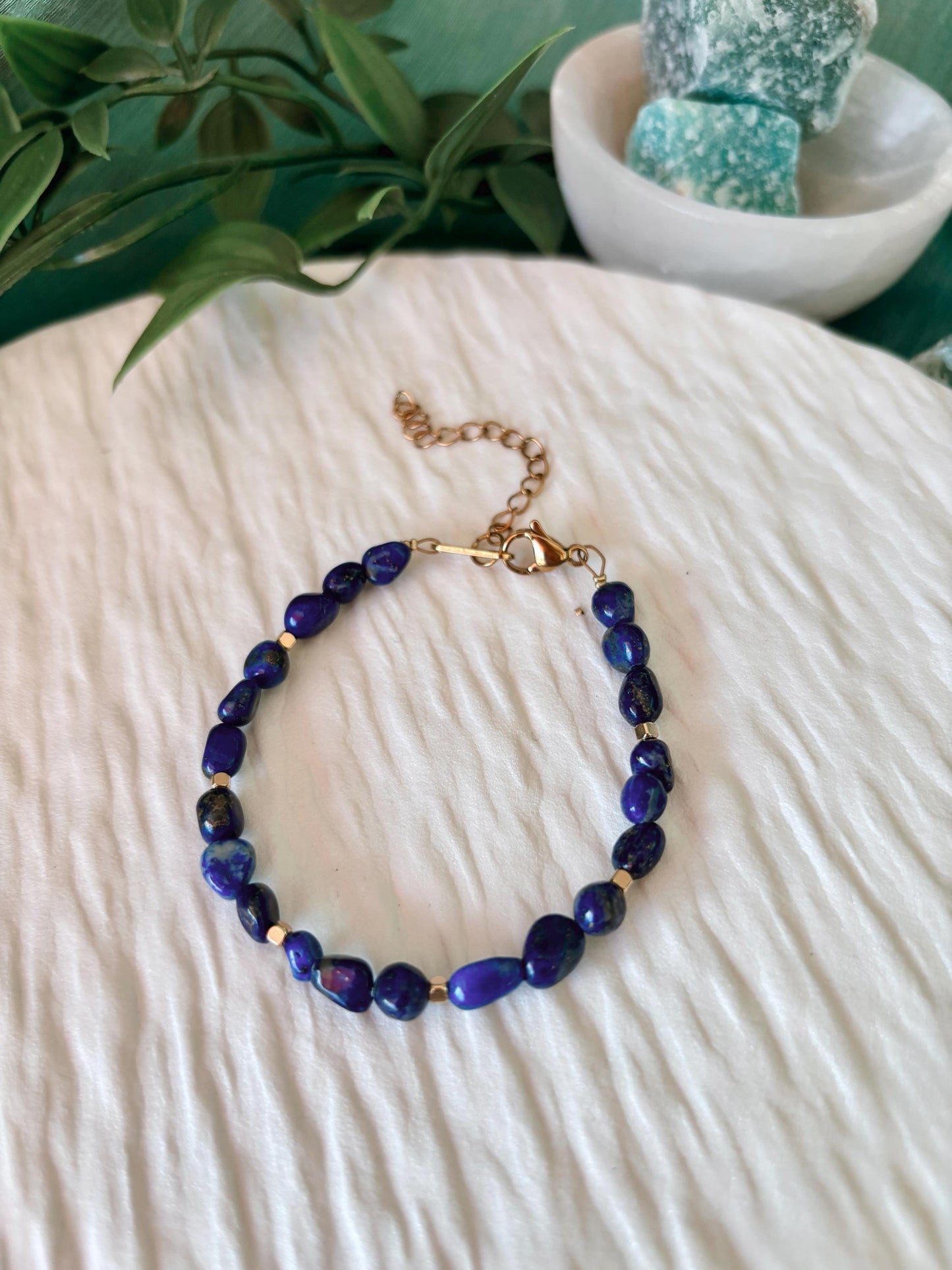 Goldenes Lapislazuli Perlenarmband mit blauen Natursteinen liegend auf weißem Tablett, Ansicht von oben