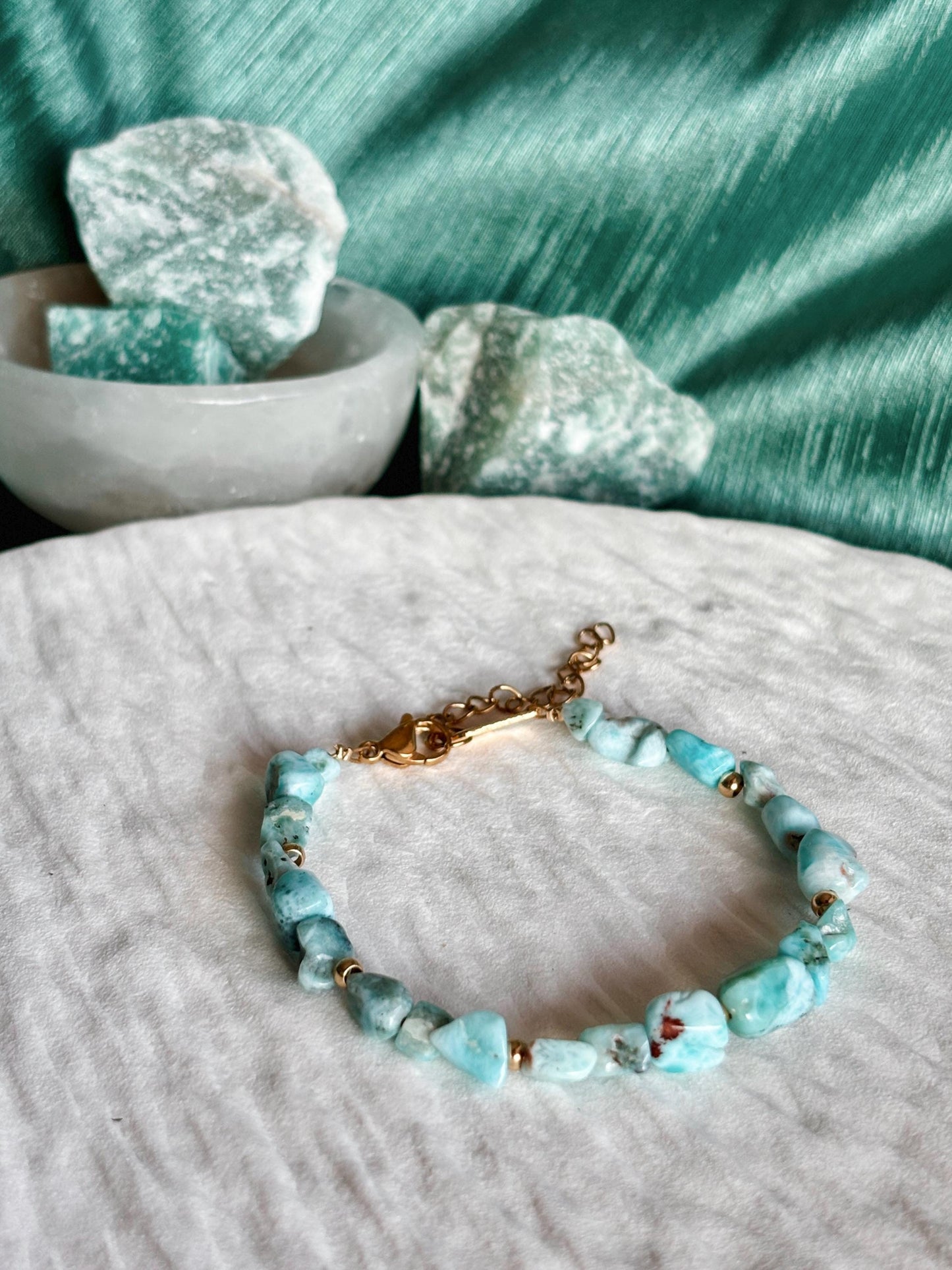 Goldenes Larimar Perlenarmband mit blauen Natursteinen liegend auf weißem Tablett, Detailaufnahme
