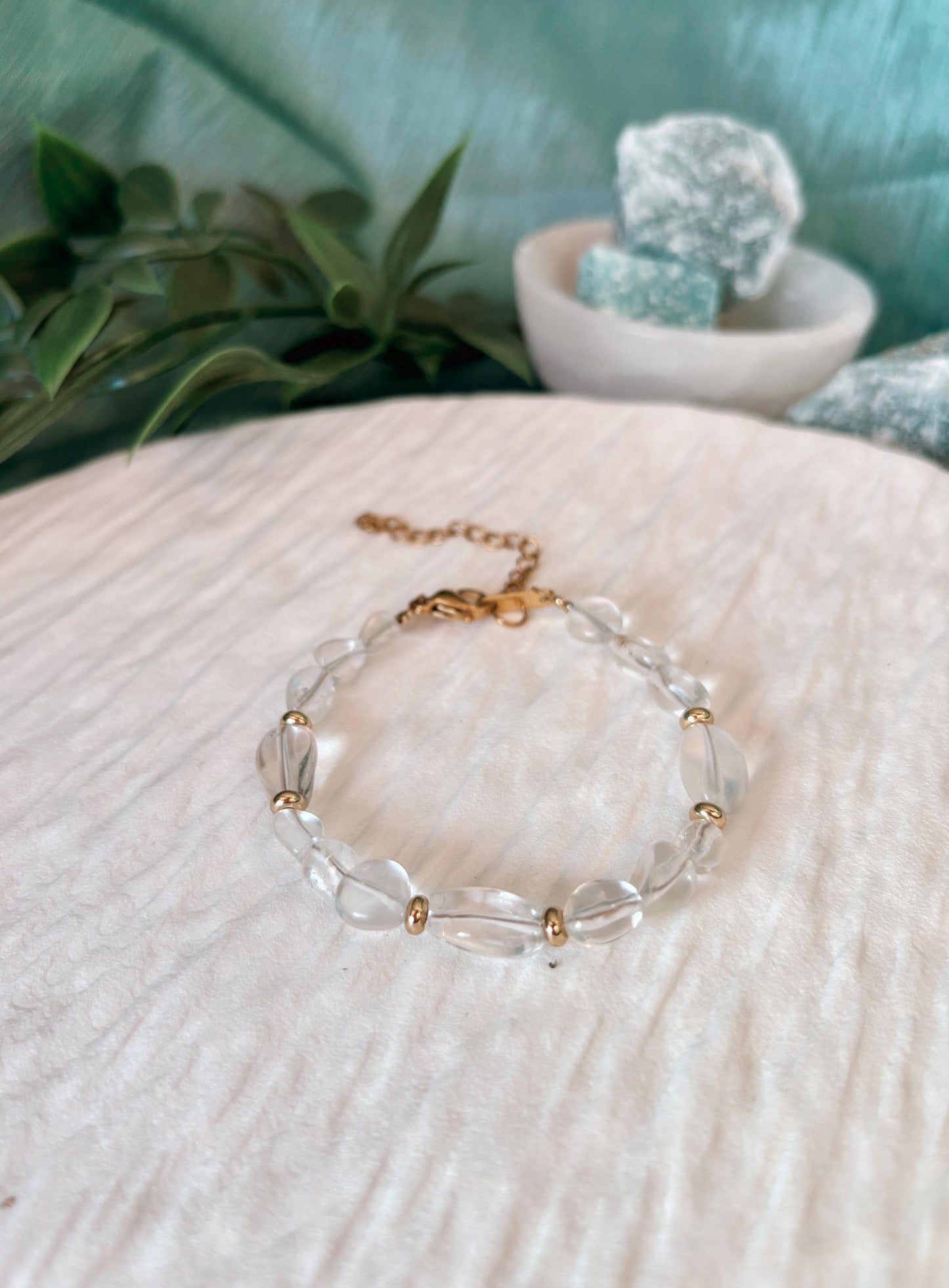 Goldenes Bergkristall Perlenarmband mit weißen Natursteinen liegend auf weißem Tablett, Detailaufnahme