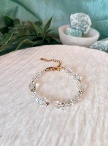 Goldenes Bergkristall Perlenarmband mit weißen Natursteinen liegend auf weißem Tablett, Detailaufnahme
