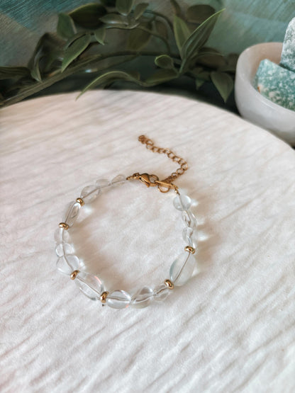 Goldenes Bergkristall Perlenarmband mit transparenten Natursteinen liegend auf weißem Tablett, Ansicht von oben