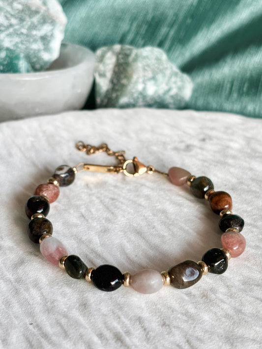 Goldenes Turmalin Perlenarmband mit bunten Natursteinen liegend auf weißem Tablett, Detailaufnahme