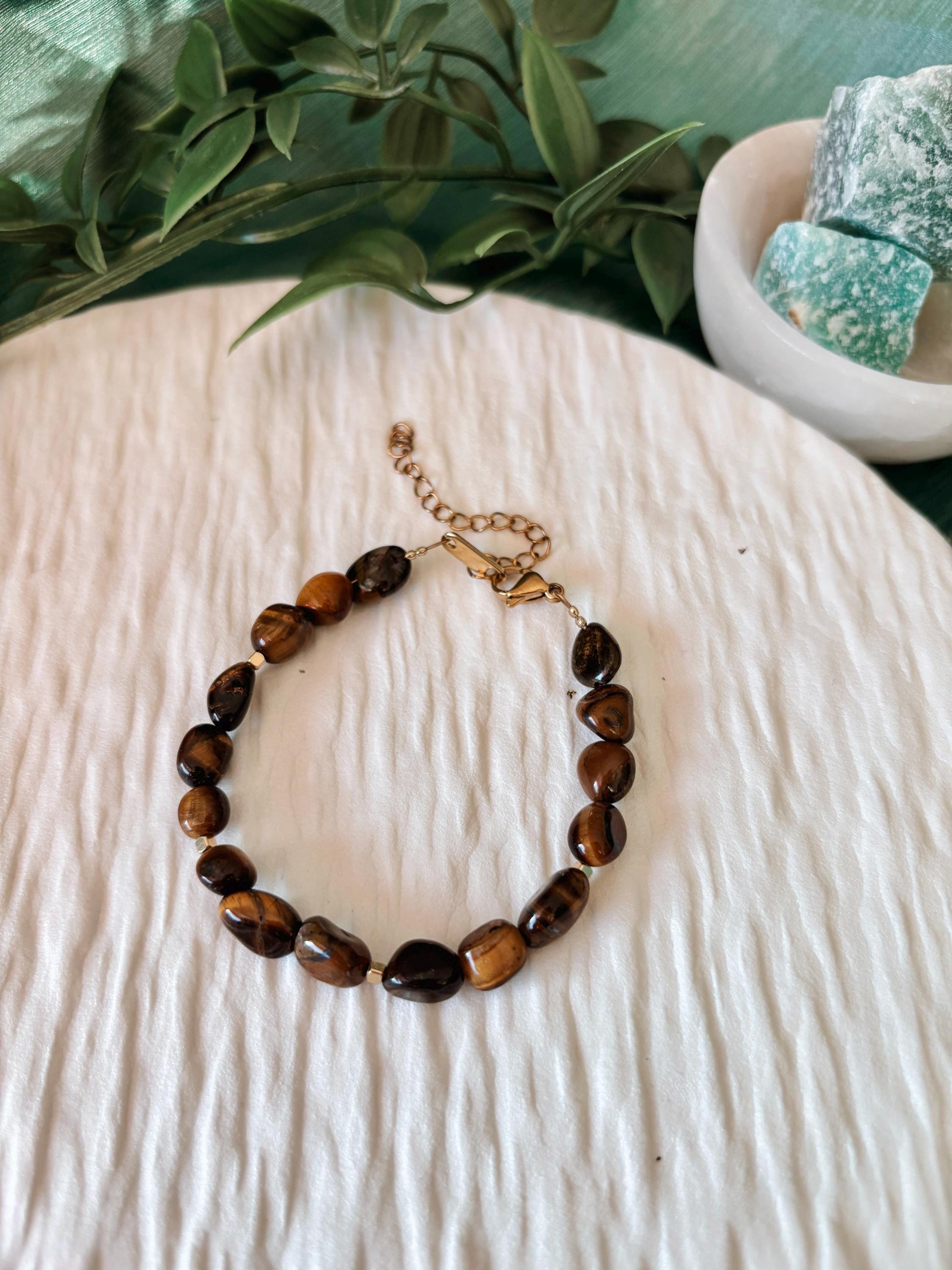 Goldenes Tigerauge Perlenarmband mit braunen Natursteinen liegend auf weißem Tablett, Ansicht von oben