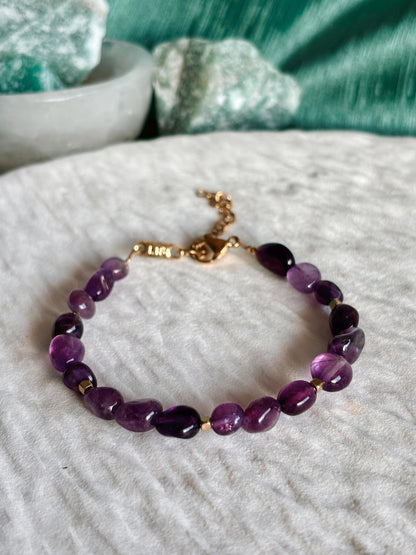 Goldenes Amethyst Perlenarmband mit lila Natursteinen liegend auf weißem Tablett, Detailaufnahme