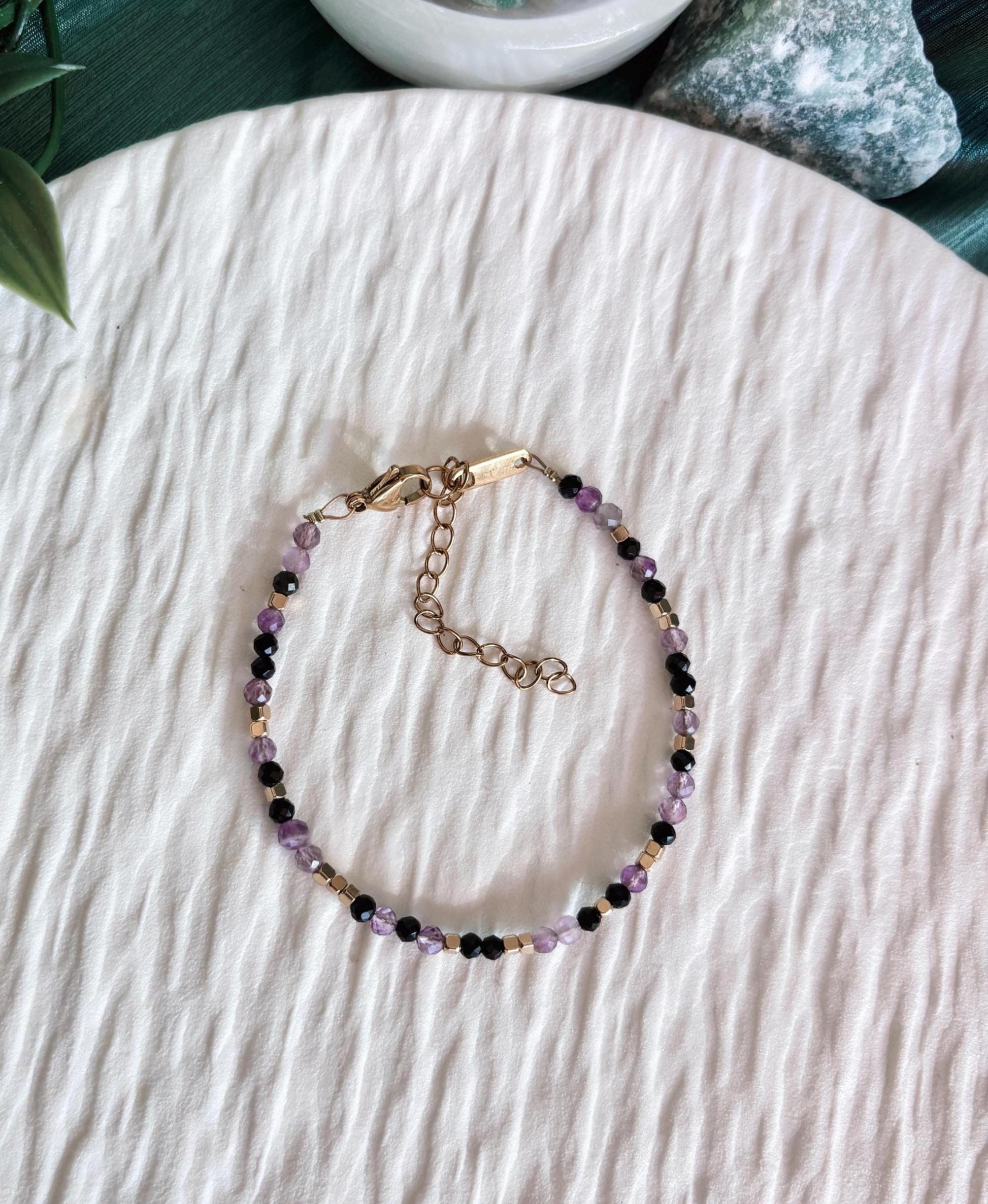 Goldenes Edelstein Armband mit Amethyst und Onyx Perlen liegend auf weißem Tablett, Ansicht von oben