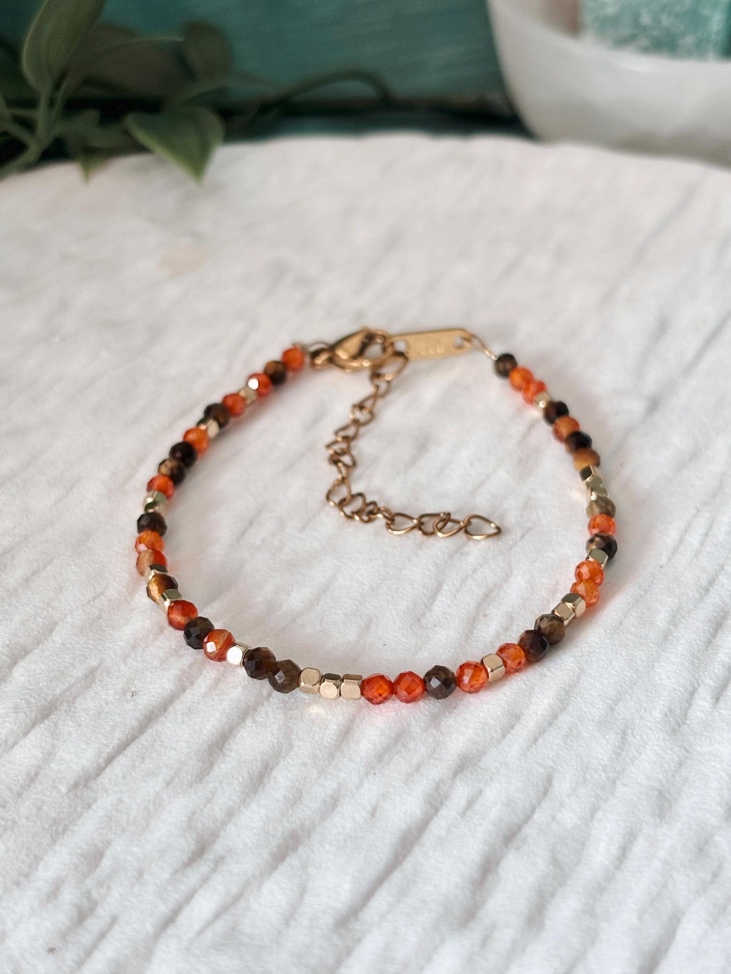 Goldenes Edelstein Armband mit Tigerauge und Karneol Perlen liegend auf weißem Tablett, Detailansicht