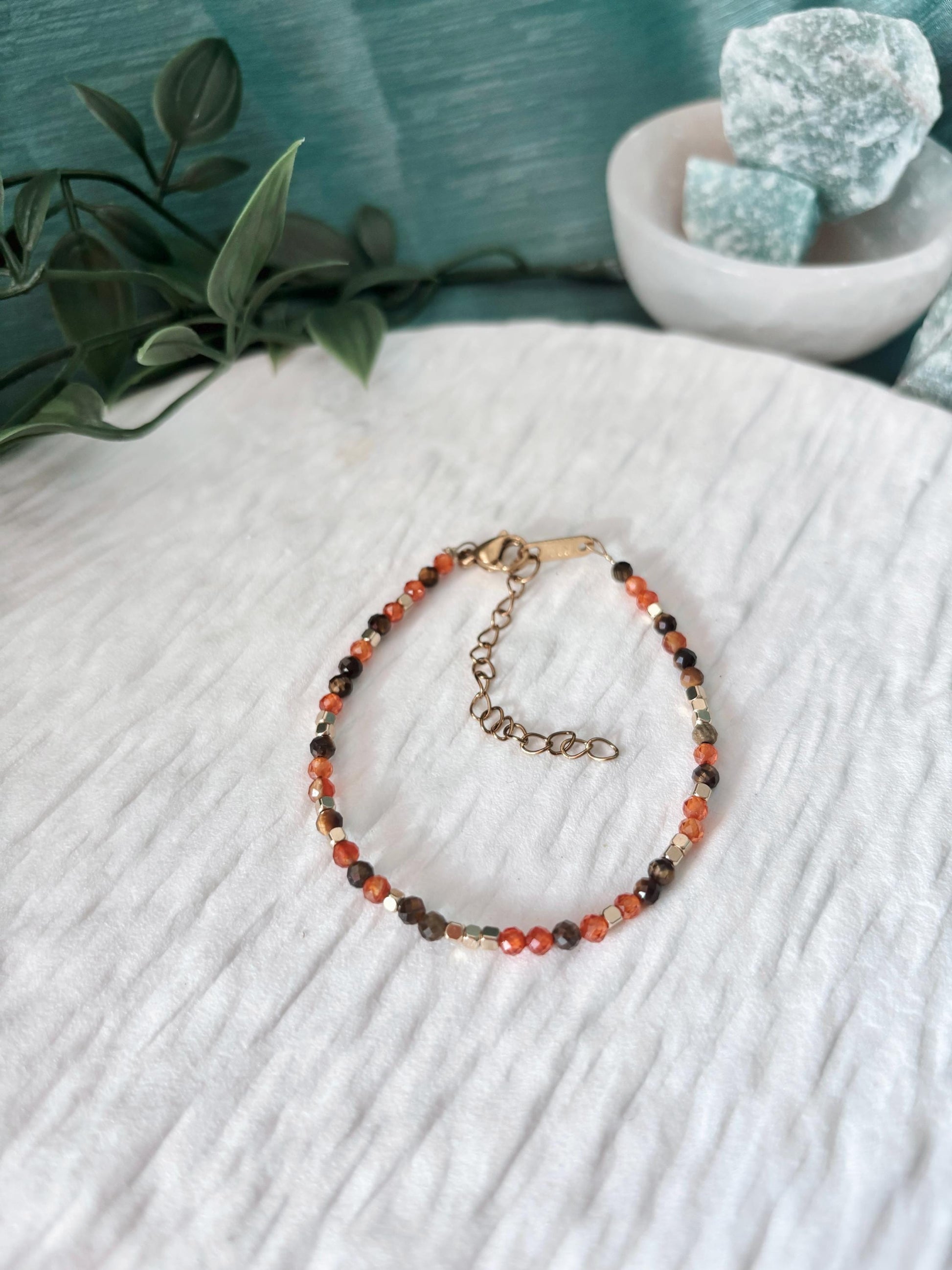 Goldenes Edelstein Armband mit Tigerauge und Karneol Perlen liegend auf weißem Tablett, Ansicht von oben