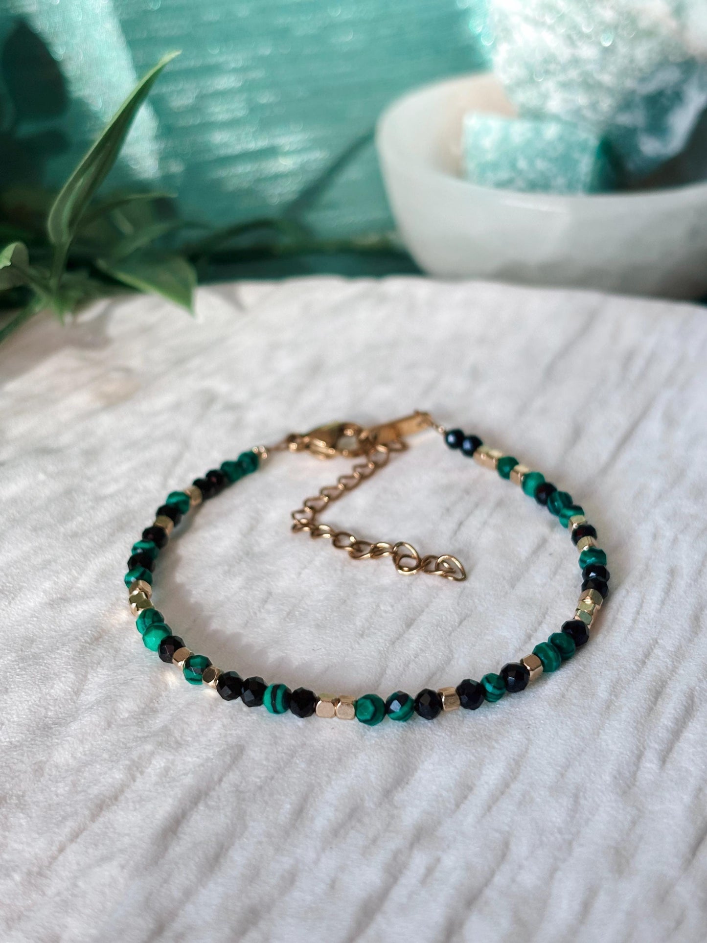 Goldenes Edelstein Armband mit Onyx und Malachit Perlen liegend auf weißem Tablett, Detailansicht