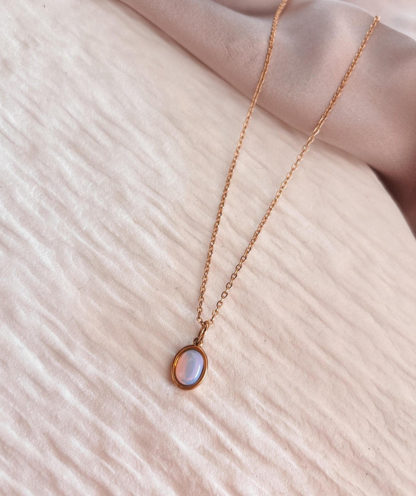 Feine Kette mit schimmerndem Opalit-Anhänger auf hellem Stoff. Produktname: Opalith-Kette Soul.