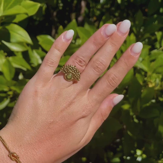 Boho Goldring mit rundem grünen Aventurin-Stein an Hand im Sonnenlicht vor Pflanzen
