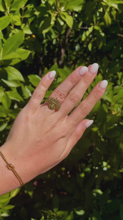 Boho Goldring mit rundem grünen Aventurin-Stein an Hand im Sonnenlicht vor Pflanzen